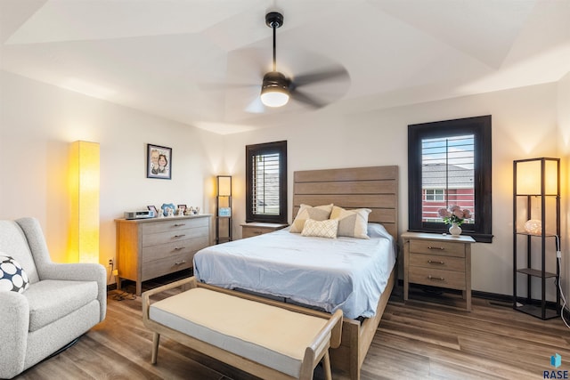 bedroom with multiple windows, dark hardwood / wood-style floors, and ceiling fan