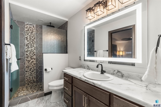 bathroom featuring vanity, a tile shower, and toilet