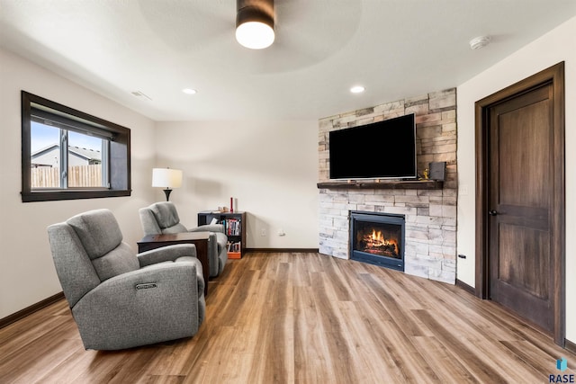 living room with hardwood / wood-style floors and a stone fireplace