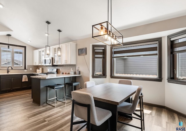 dining area featuring lofted ceiling, sink, and light hardwood / wood-style floors