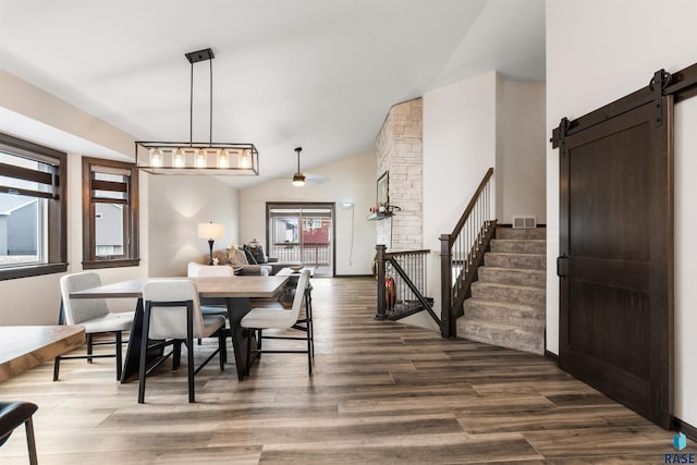 dining area with hardwood / wood-style flooring, a barn door, and vaulted ceiling