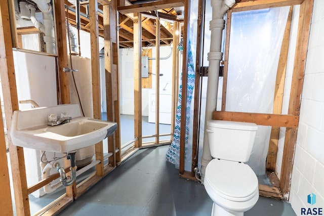 bathroom featuring washer / dryer, sink, concrete floors, and toilet