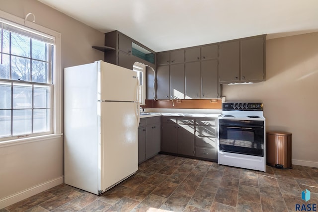 kitchen with white refrigerator, gray cabinetry, a wealth of natural light, and electric range