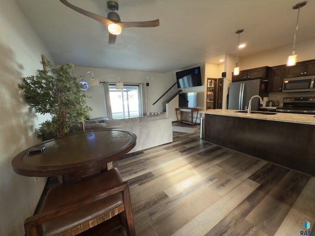 interior space featuring dark brown cabinetry, sink, decorative light fixtures, dark hardwood / wood-style floors, and stainless steel appliances