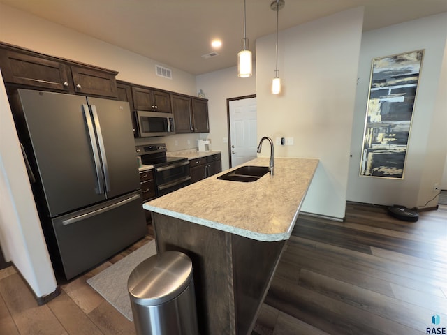 kitchen featuring pendant lighting, sink, dark brown cabinetry, stainless steel appliances, and dark wood-type flooring