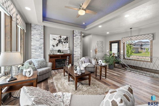 living room with a tray ceiling, a textured ceiling, ceiling fan, and hardwood / wood-style flooring