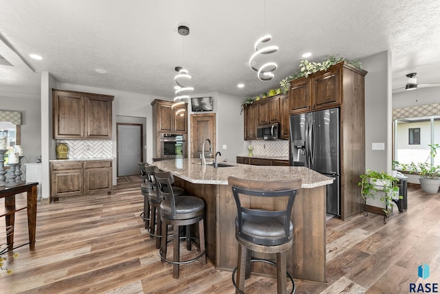 kitchen featuring appliances with stainless steel finishes, an island with sink, and backsplash