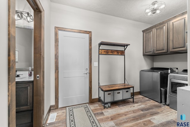 laundry room featuring sink, cabinets, hardwood / wood-style flooring, washing machine and dryer, and a textured ceiling