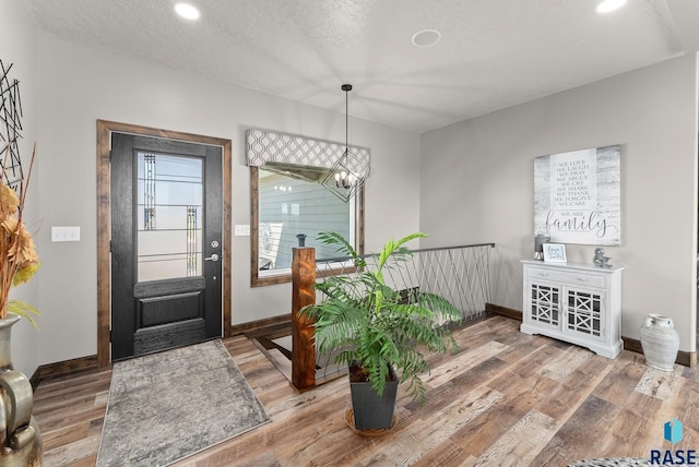 entryway with wood-type flooring, a chandelier, and a textured ceiling