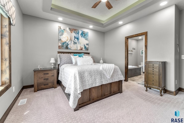 carpeted bedroom featuring ceiling fan, a tray ceiling, and connected bathroom