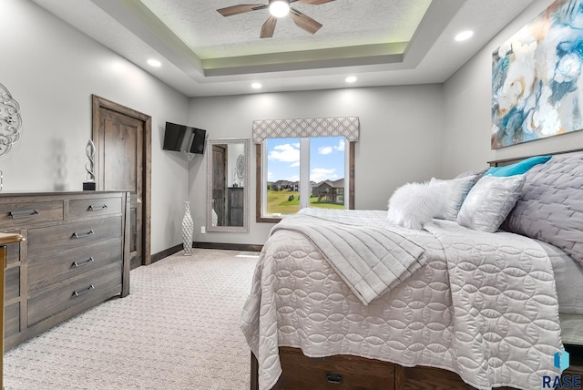 carpeted bedroom with a tray ceiling, a textured ceiling, and ceiling fan