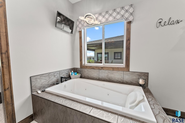 bathroom featuring tiled tub and a chandelier