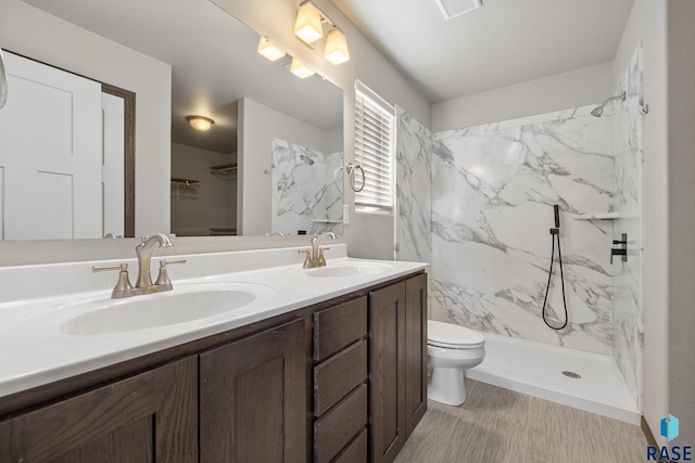 bathroom featuring vanity, tiled shower, and toilet