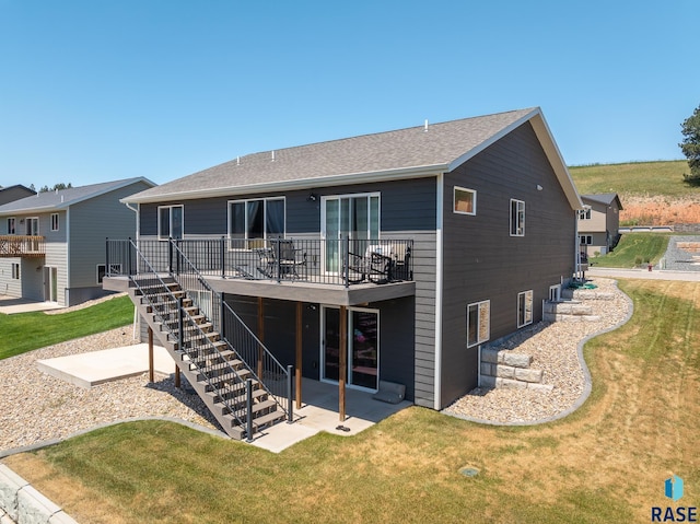 rear view of property featuring a wooden deck, a yard, and a patio area