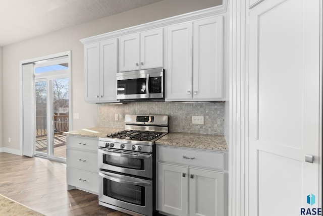 kitchen with tasteful backsplash, appliances with stainless steel finishes, light stone countertops, and white cabinets