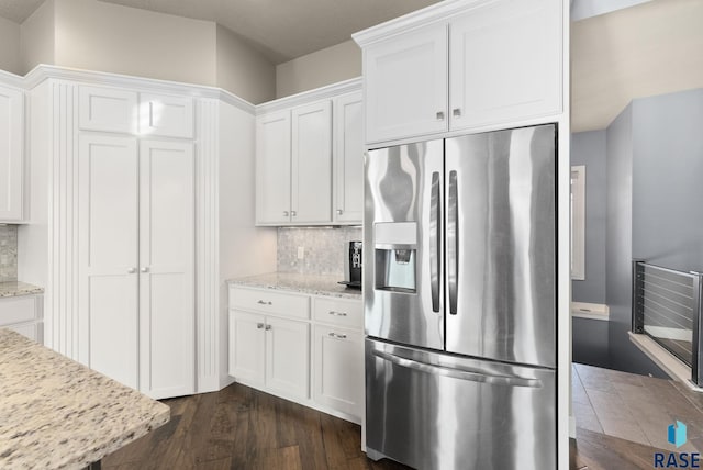 kitchen with white cabinetry, stainless steel fridge with ice dispenser, dark hardwood / wood-style flooring, light stone countertops, and decorative backsplash