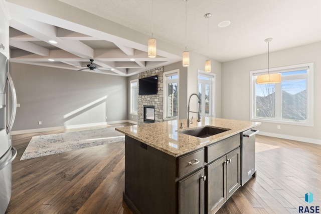 kitchen with dark brown cabinetry, coffered ceiling, sink, decorative light fixtures, and beam ceiling