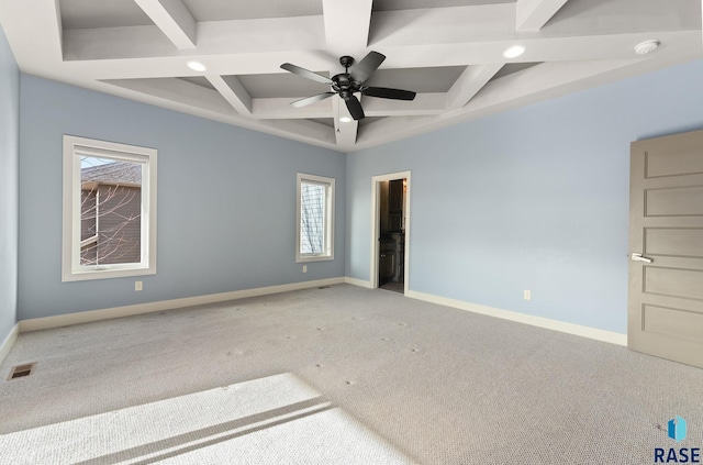 carpeted spare room featuring coffered ceiling, beam ceiling, plenty of natural light, and ceiling fan