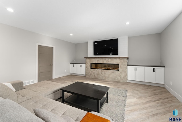 living room with a fireplace and light wood-type flooring