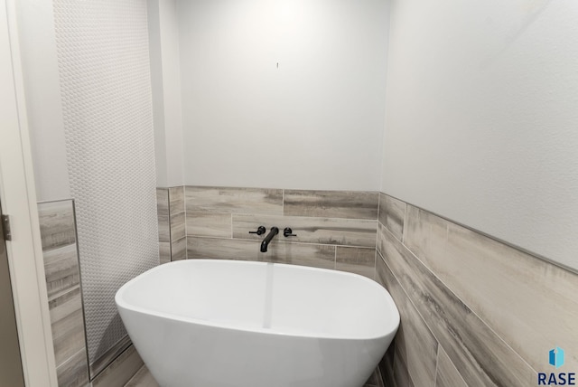 bathroom featuring tile walls and a bathtub