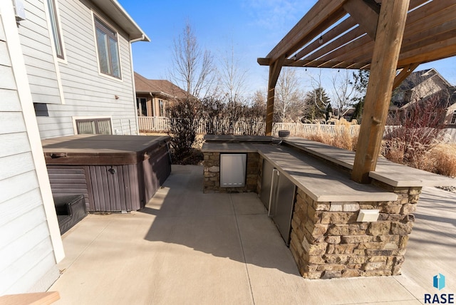 view of patio featuring a pergola, a hot tub, and an outdoor kitchen