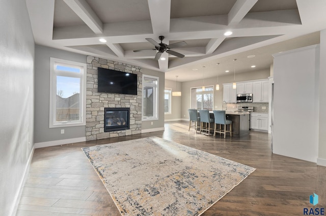 living room with coffered ceiling, dark wood-type flooring, a fireplace, and ceiling fan