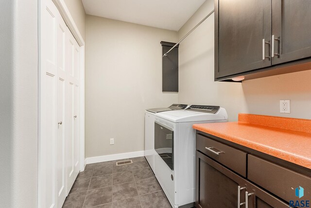 laundry area featuring cabinets, washer and clothes dryer, and dark tile patterned flooring