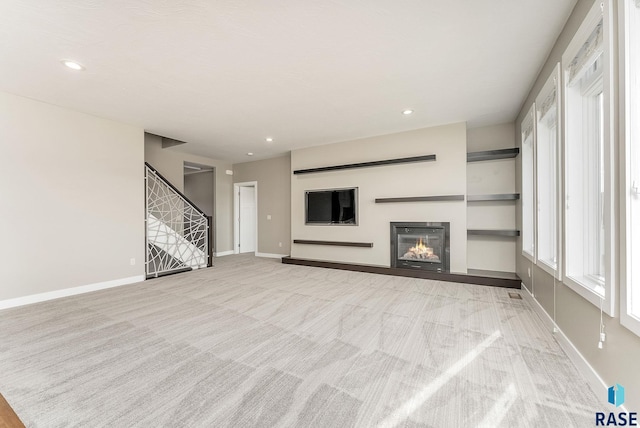 unfurnished living room featuring built in features and light colored carpet