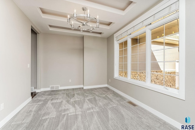 unfurnished room featuring an inviting chandelier, light carpet, and a raised ceiling