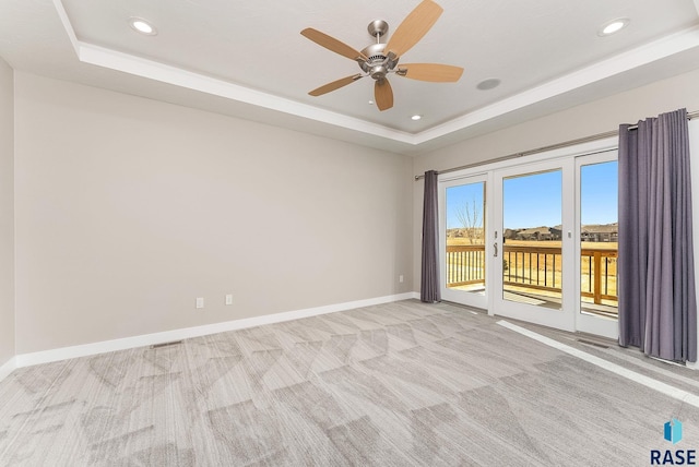 carpeted spare room featuring a tray ceiling and ceiling fan