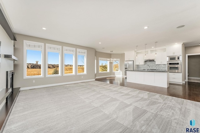 unfurnished living room featuring plenty of natural light and sink