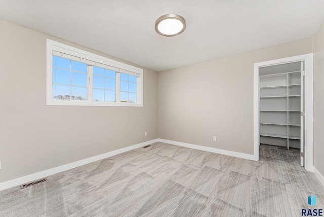 unfurnished bedroom with a spacious closet and light carpet