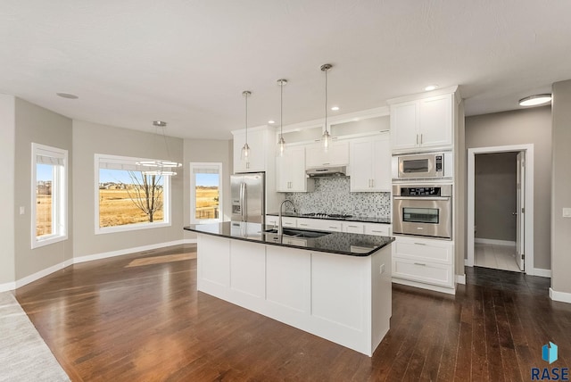 kitchen featuring sink, white cabinetry, decorative light fixtures, appliances with stainless steel finishes, and an island with sink