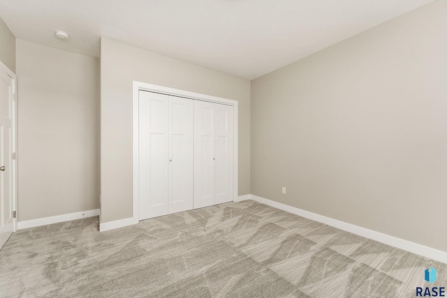 unfurnished bedroom with light colored carpet and a closet