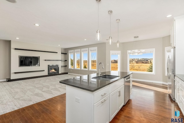 kitchen featuring white cabinetry, sink, dark stone counters, a kitchen island with sink, and stainless steel appliances