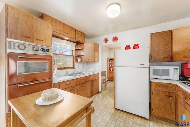 kitchen with backsplash, white appliances, and sink