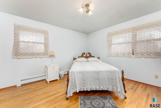 bedroom with a baseboard radiator, a chandelier, and light wood-type flooring