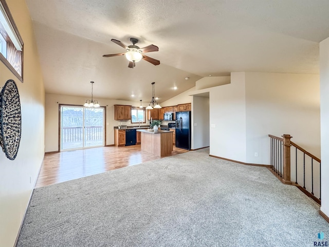 kitchen featuring vaulted ceiling, a kitchen island, ceiling fan with notable chandelier, decorative light fixtures, and black appliances