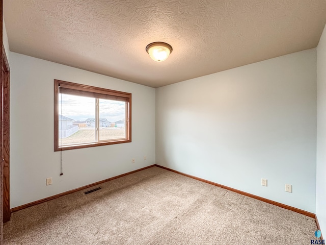 carpeted empty room with a textured ceiling