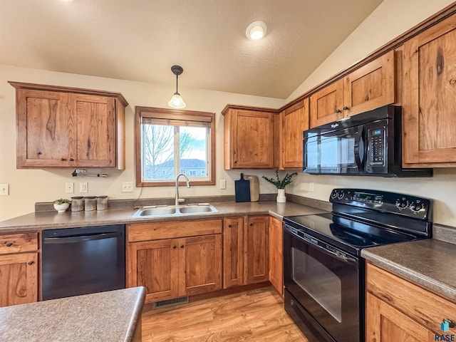 kitchen with lofted ceiling, sink, black appliances, light hardwood / wood-style floors, and decorative light fixtures