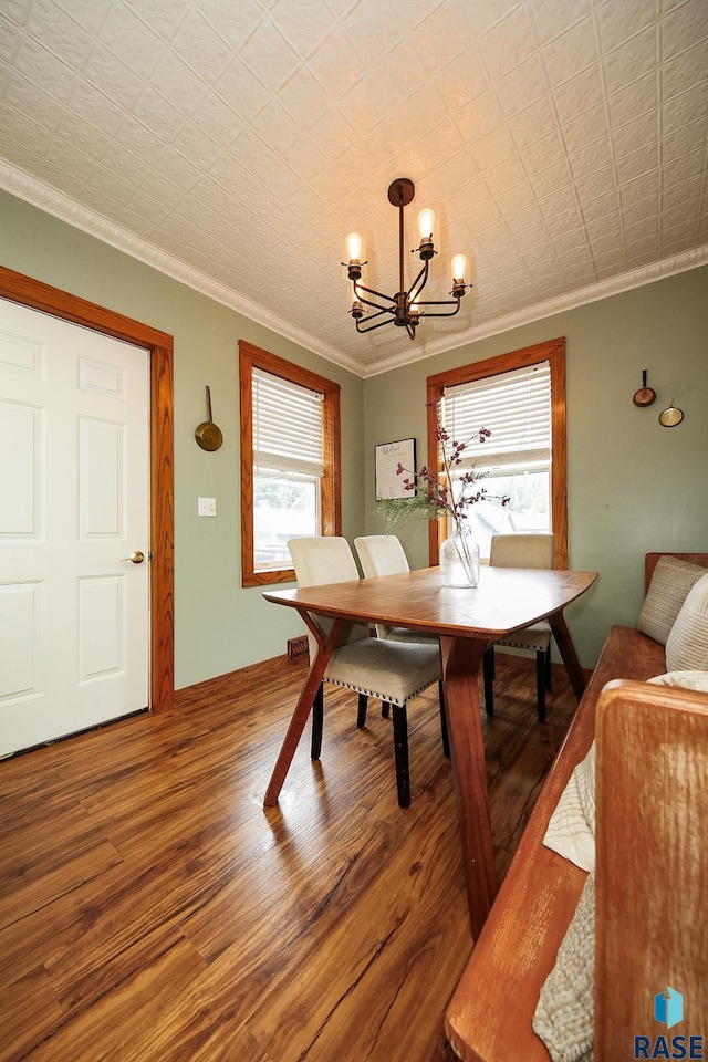 dining space featuring crown molding, a wealth of natural light, hardwood / wood-style floors, and an inviting chandelier