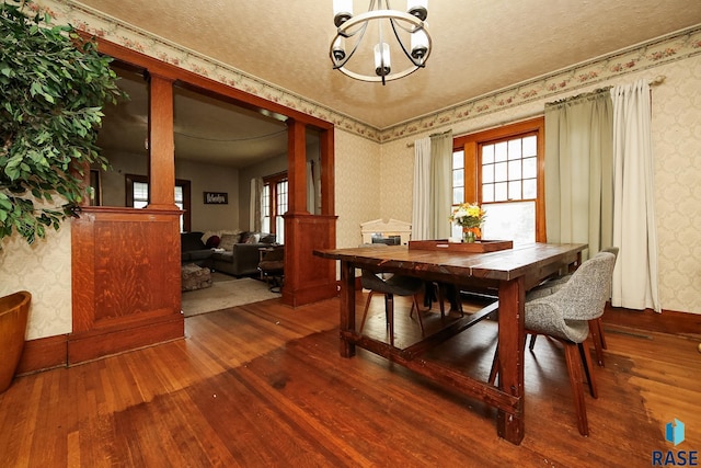 dining area with hardwood / wood-style flooring, a textured ceiling, and a notable chandelier