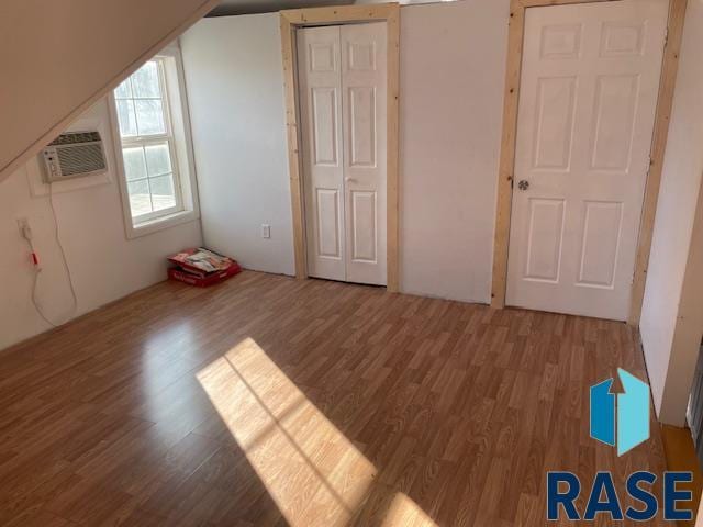 additional living space with hardwood / wood-style flooring and cooling unit