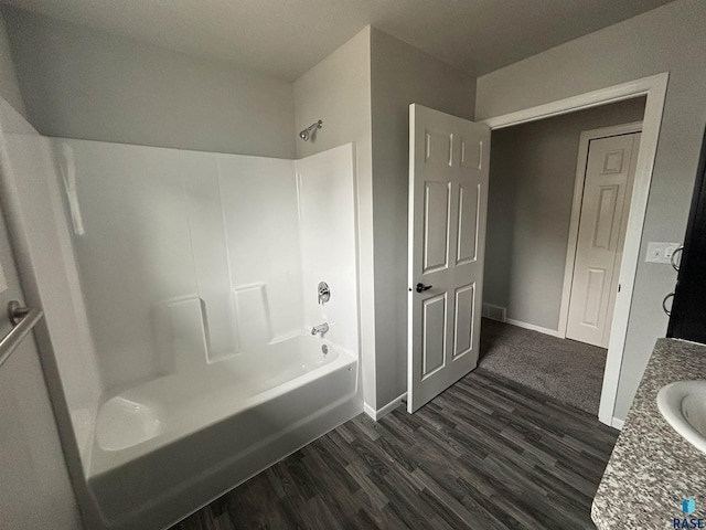 bathroom with hardwood / wood-style flooring, washtub / shower combination, and vanity