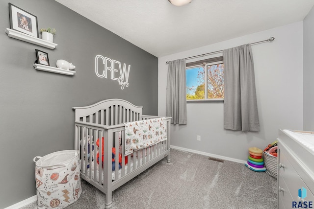 carpeted bedroom featuring a nursery area