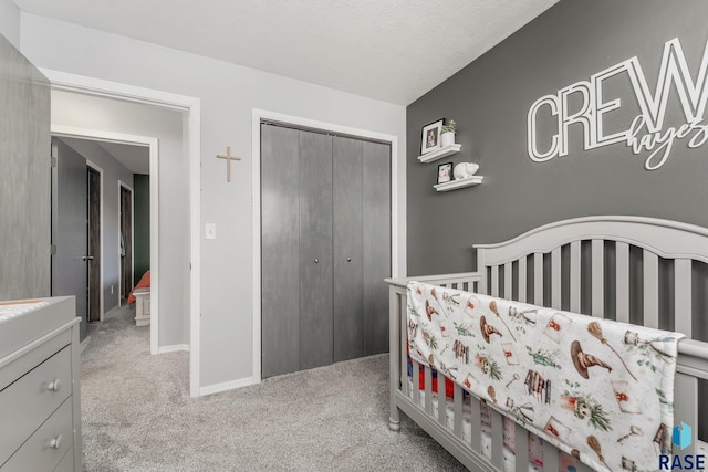 bedroom with a nursery area, light carpet, and a closet