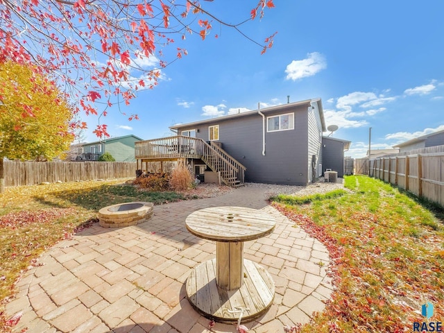 back of house featuring a wooden deck, a patio area, central air condition unit, and an outdoor fire pit