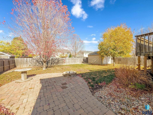 view of yard featuring a storage shed, a patio area, and an outdoor fire pit