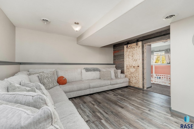 living room featuring a barn door, hardwood / wood-style floors, and wooden walls