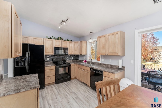 kitchen featuring vaulted ceiling, decorative light fixtures, sink, black appliances, and light brown cabinets